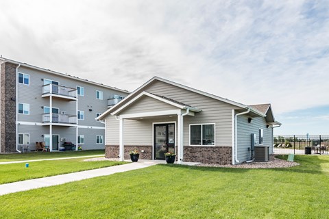 A modern two-story apartment building with a well-maintained lawn in front.